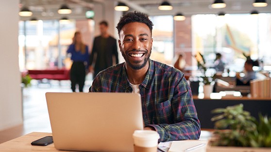 Man smiling while working on computer in office after teeth whitening in Colchester