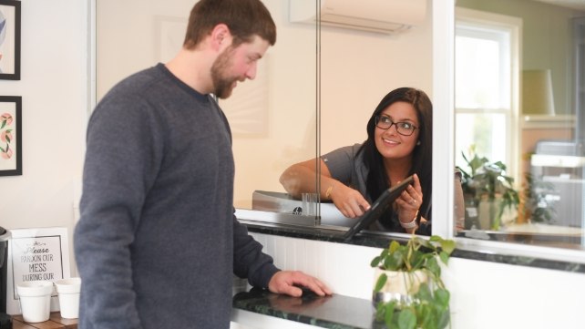 Dental team member talking to a patient at front desk of Colchester dental office