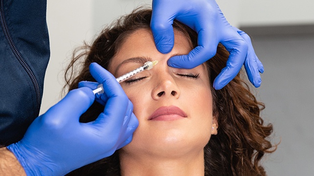 Woman having BOTOX® injected in forehead