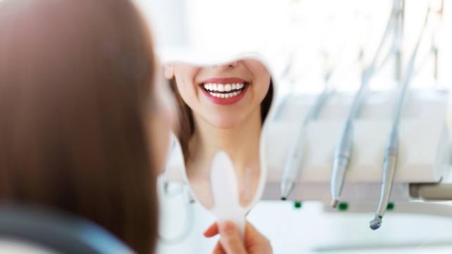 Woman looking at smile after receiving cosmetic dental restorations