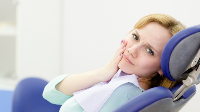 Woman holding cheek in pain before tooth extraction