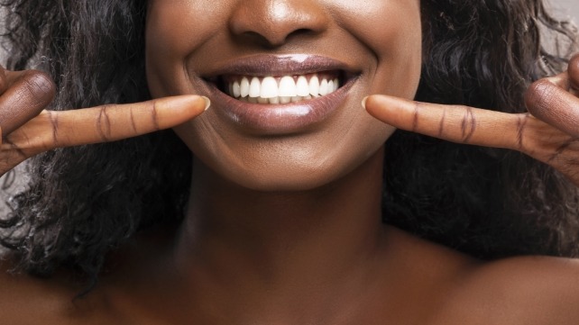 Woman pointing to healthy smile after gum disease treatment