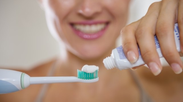 Person putting toothpaste onto a toothbrush