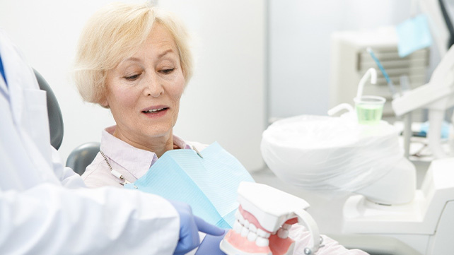 implant dentist in Colchester showing a denture to a patient