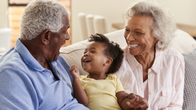 Grandparents smiling at grandchild and enjoying the benefits of dental implants