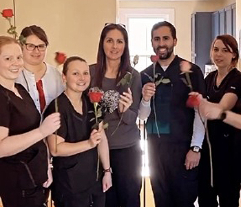 Dental team members in dental office holding roses