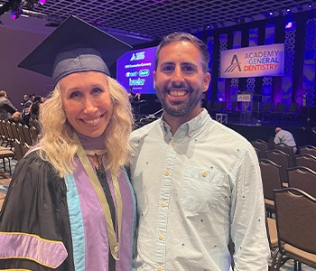 Doctor Kristen in graduation robes smiling with Doctor Mike