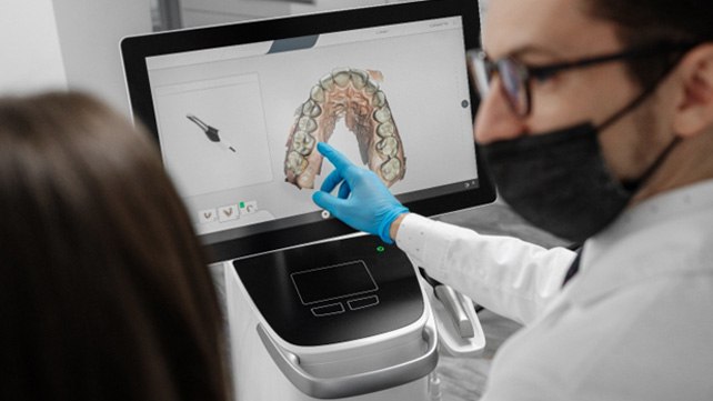 Dentist looking at results from an iTero scanner with his patient