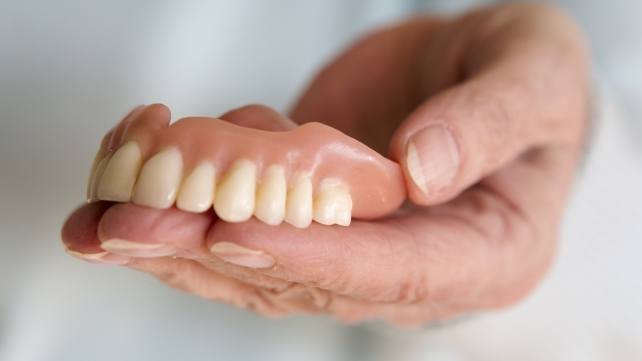 Hand holding full dentures