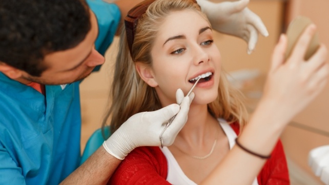 Dentist and patient looking at smile after veneer treatment