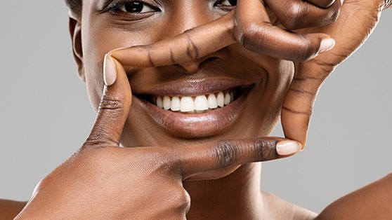 Woman framing her white teeth with her hands