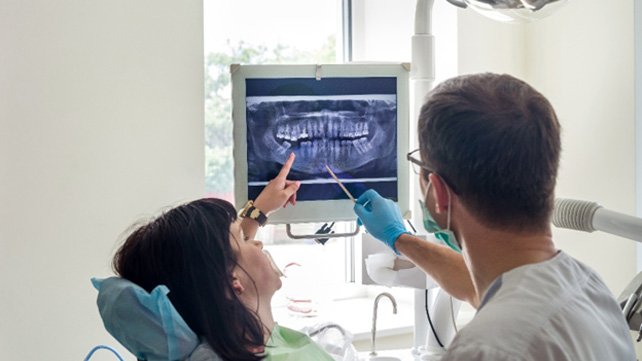 Patient and dentist examining digital X-Ray together