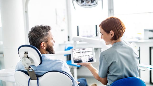 Happy patient and dental team member looking at dental x ray